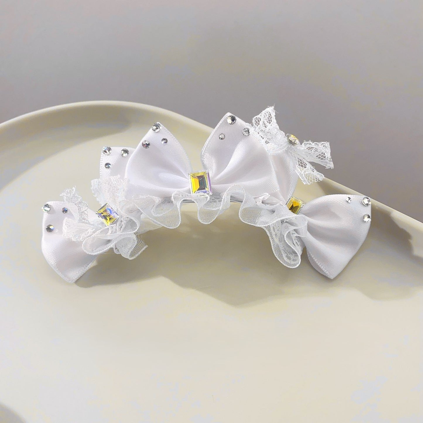 White satin pet hair bow accessory with lace trim, rhinestone-style accents, and crystal center detail