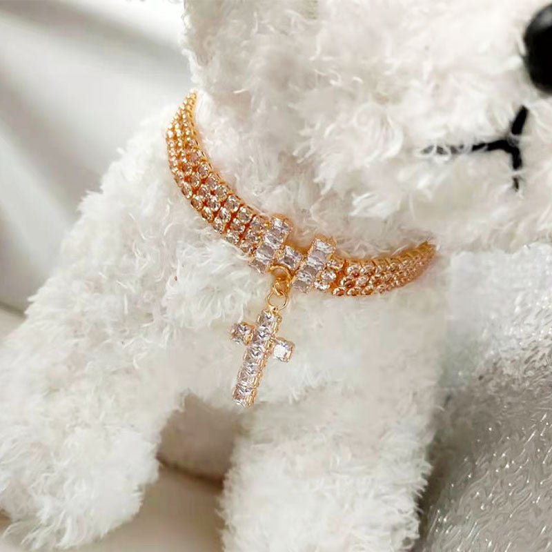 Small white dog wearing a gold-tone cross pendant pet necklace