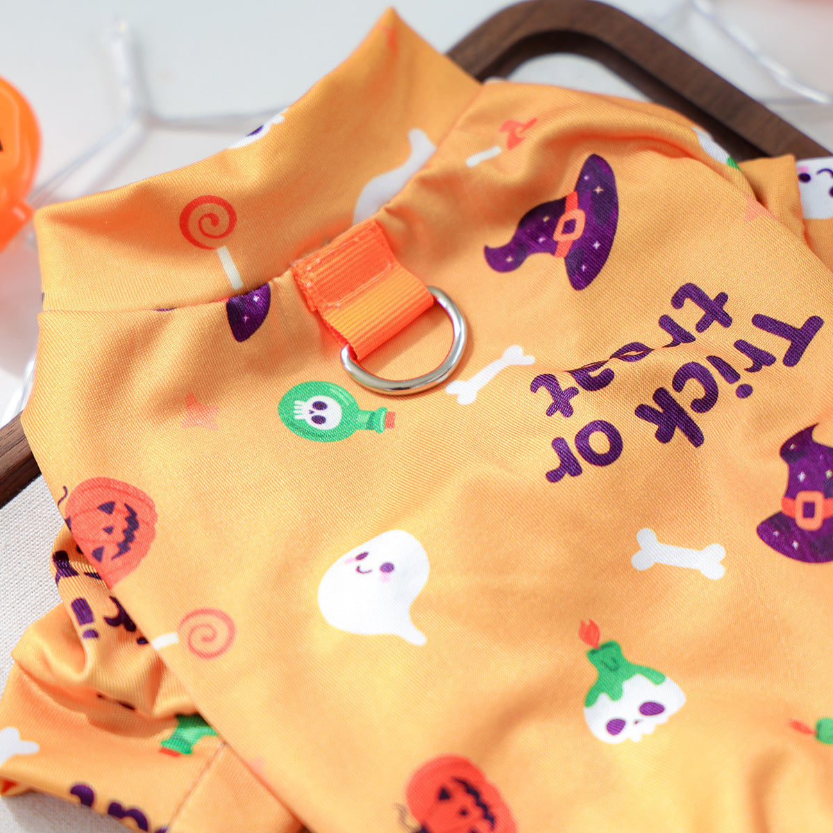 Close-up of orange Halloween pet pajamas with silver metal ring and Trick or Treat print