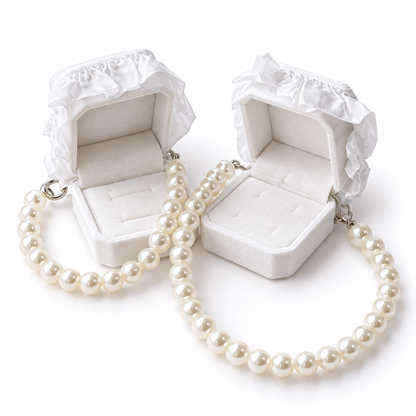 Open white wedding ring boxes attached to pearl-look pet necklaces