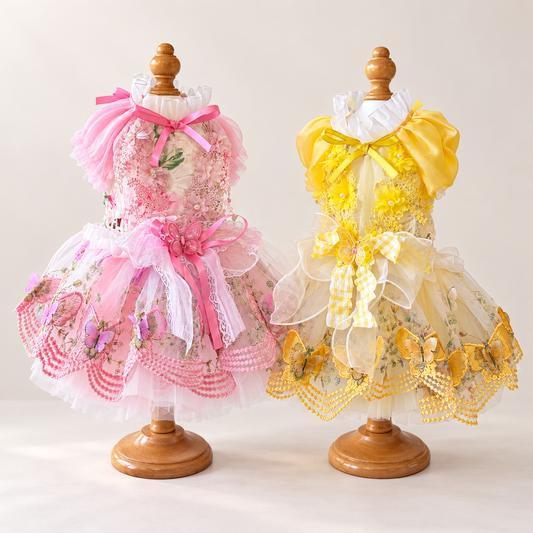 Pink and yellow handmade butterfly pet dresses displayed side by side