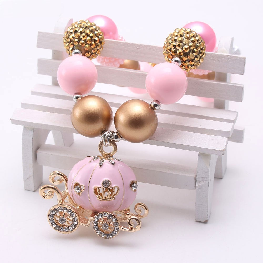 Close view of pink pumpkin carriage pendant and mixed gold beads