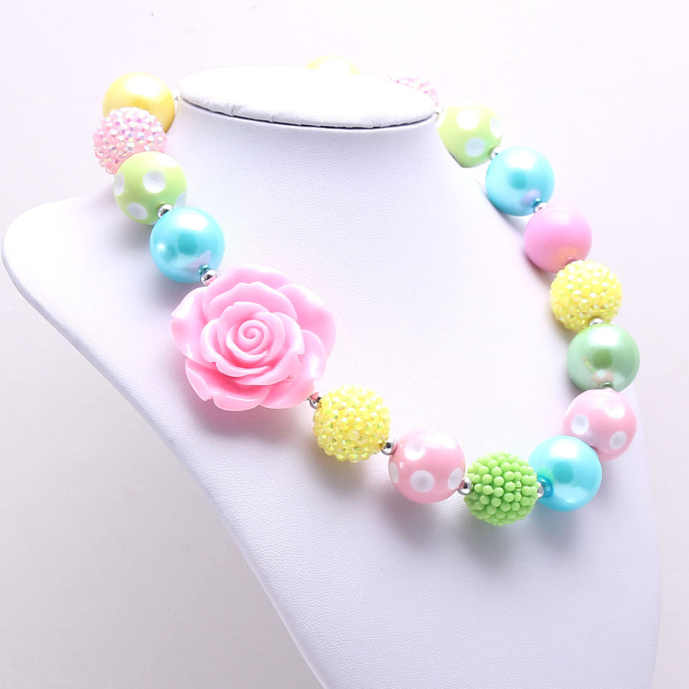 Angled view of pastel acrylic bead dog necklace with large pink rose