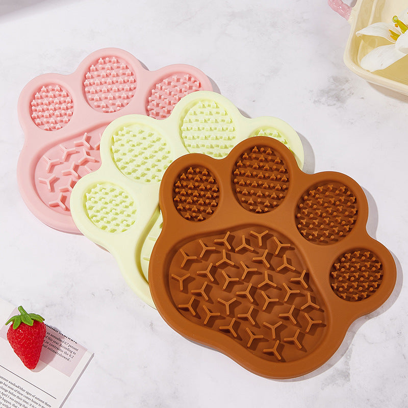 Brown pink and light yellow paw silicone slow feeder mats on a tabletop