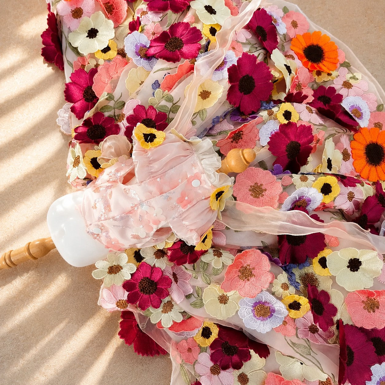 Close up of pink floral embroidered pet dress with sheer organza ribbons and colorful flower appliques