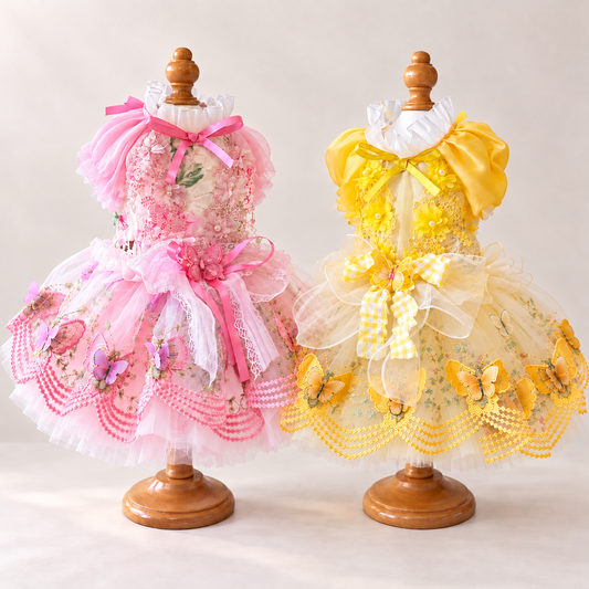 Pink and yellow handmade butterfly pet dresses displayed side by side