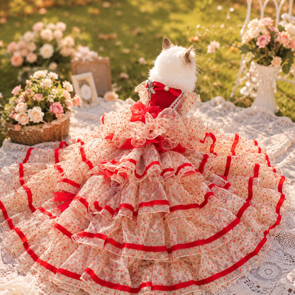 Cat wearing luxury red and ivory pet wedding gown with dramatic cathedral-style long train in outdoor garden setting