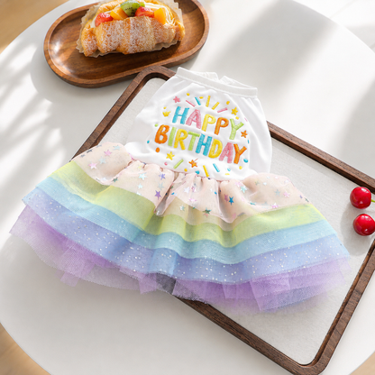 Flat lay of Happy Birthday dog dress with white bodice and pastel rainbow tulle skirt
