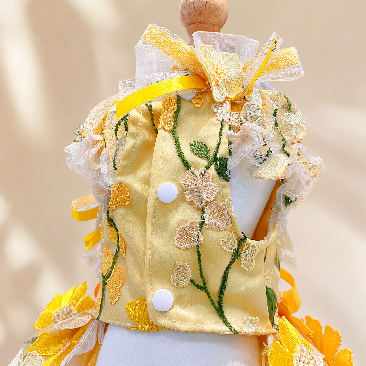 Back detail of yellow floral pet gown with buttons, ribbons, and sheer ruffles