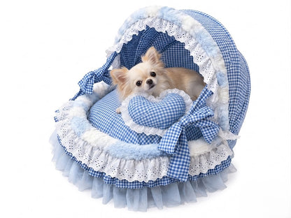 Small dog resting inside blue gingham princess pet bed with lace canopy and heart pillow