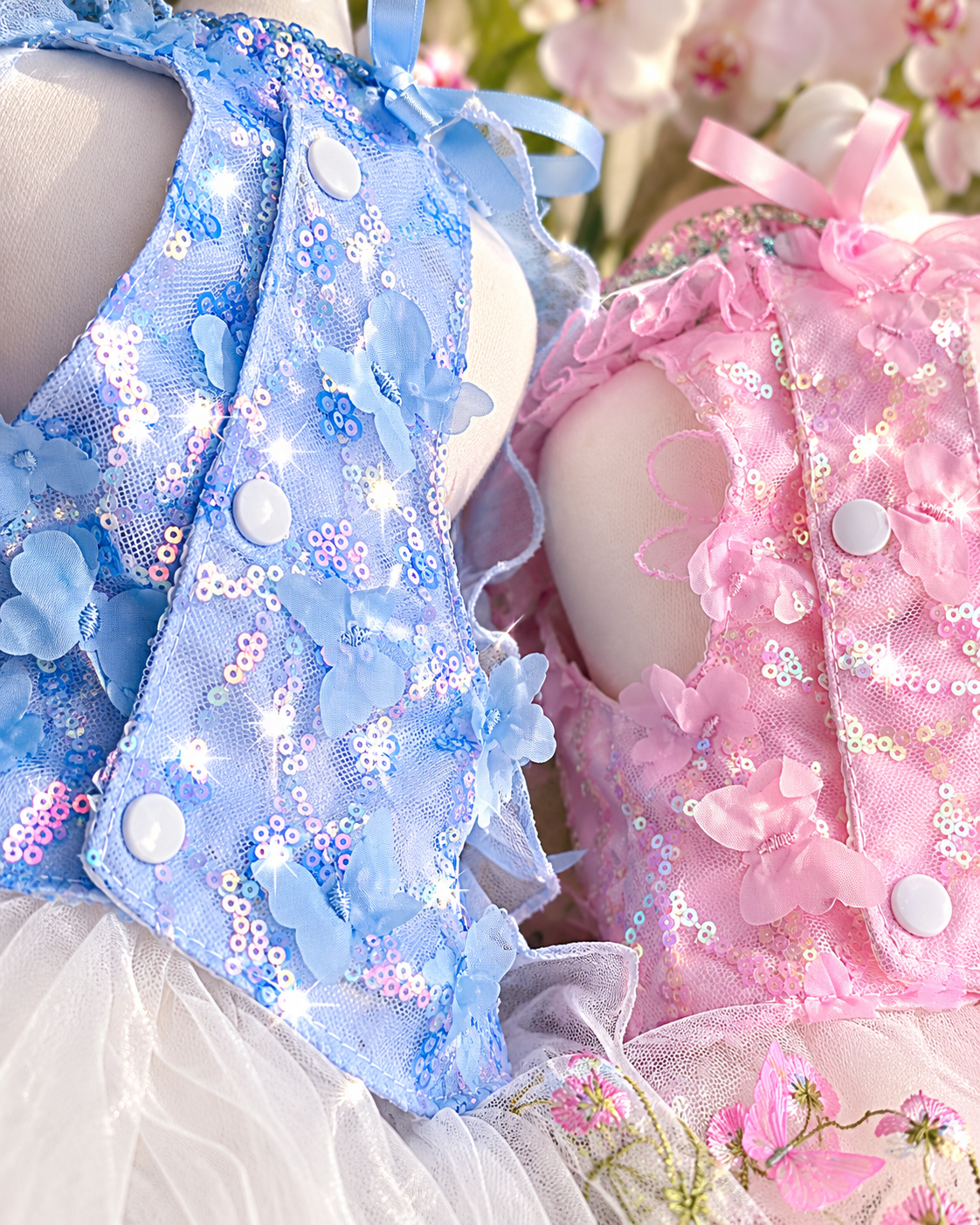 Close-up of blue and pink pet dress bodices with sequins butterflies and buttons