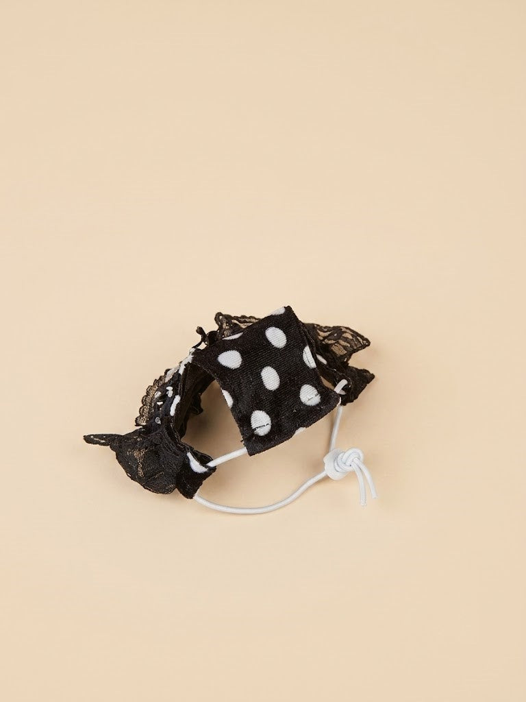 Black polka dot lace pet bonnet accessory with white elastic cord on beige background