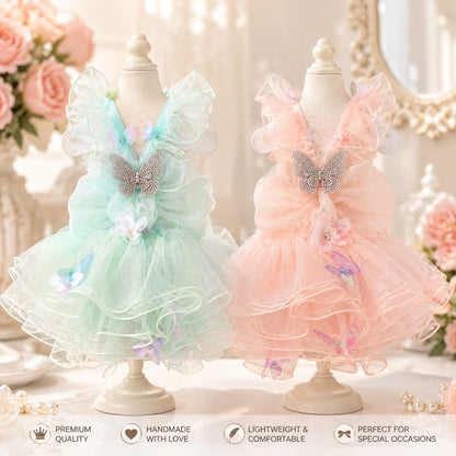 Small white dog wearing blush pink butterfly fairy princess dress with layered tulle skirt, rhinestone butterfly accent, and floral embellishments