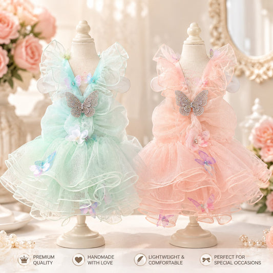 Small white dog wearing blush pink butterfly fairy princess dress with layered tulle skirt, rhinestone butterfly accent, and floral embellishments