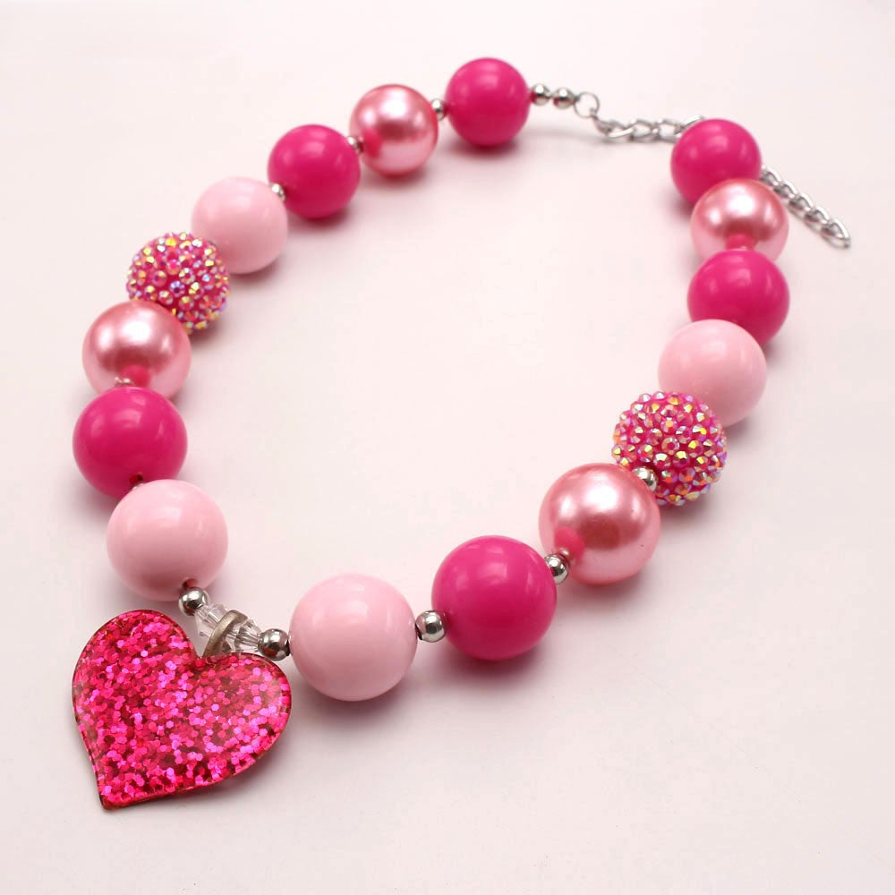 Angled view of hot pink beaded dog necklace with glitter heart charm