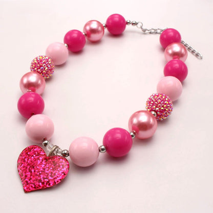 Angled view of hot pink beaded dog necklace with glitter heart charm