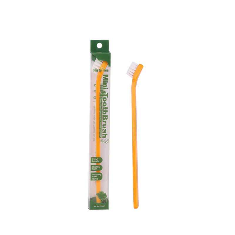 Orange mini pet toothbrush beside green and white package