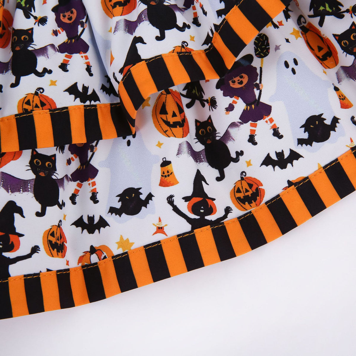 Close-up of Halloween pet dress fabric with pumpkins witches black cats ghosts bats and striped trim