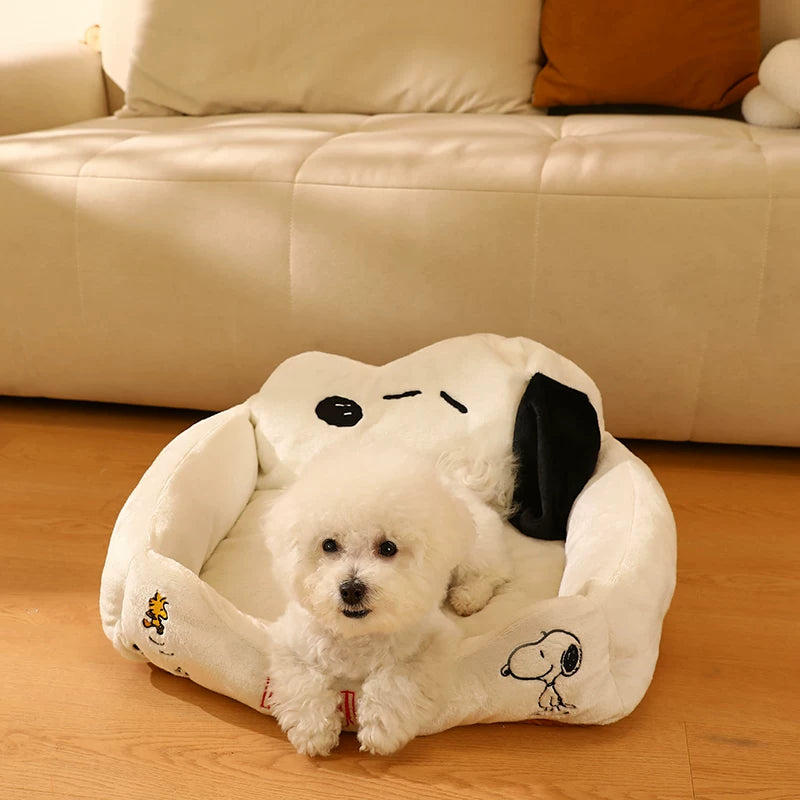Small dog lying behind the low front edge of a Snoopy sofa pet bed
