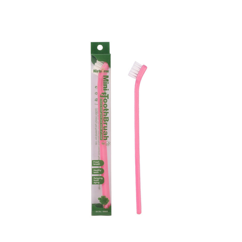 Pink mini pet toothbrush beside green and white package