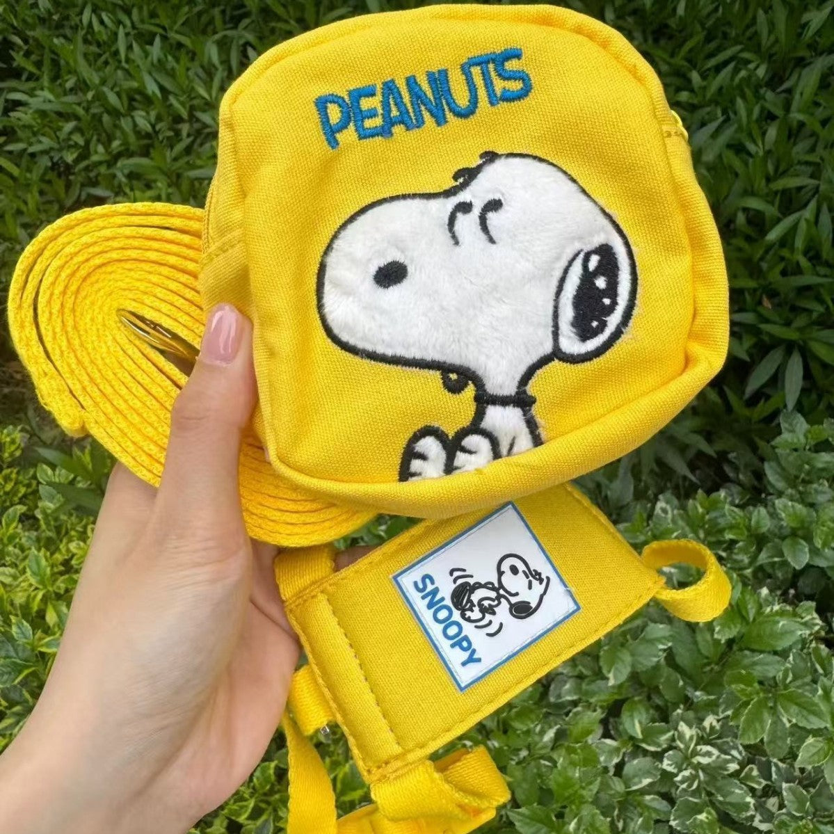 Close-up of yellow cartoon dog backpack harness with leash and front patch