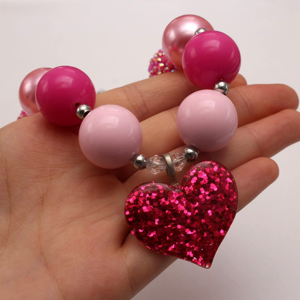 Close-up of pink glitter heart pendant and glossy acrylic beads