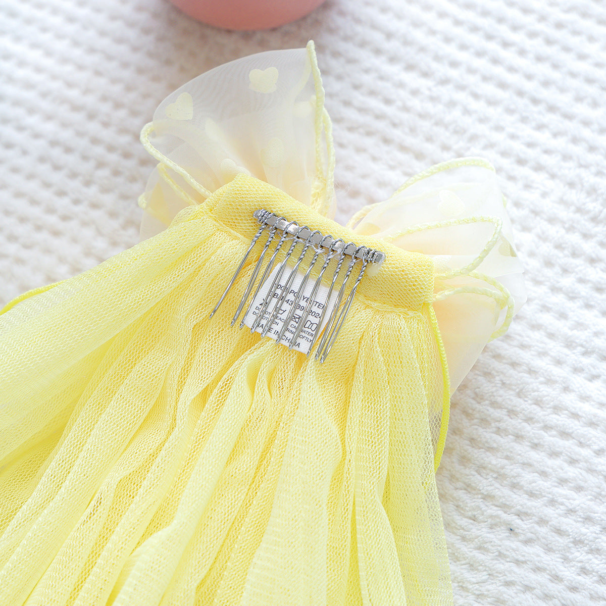 Back of yellow tulle pet veil showing metal comb attachment