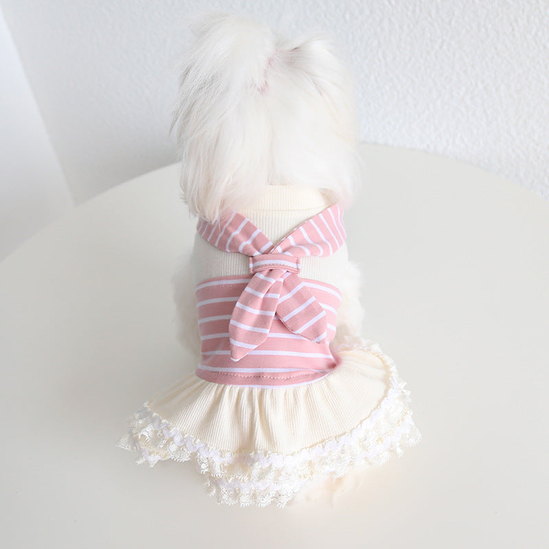 Small white dog modeling the pink sailor dress from the back