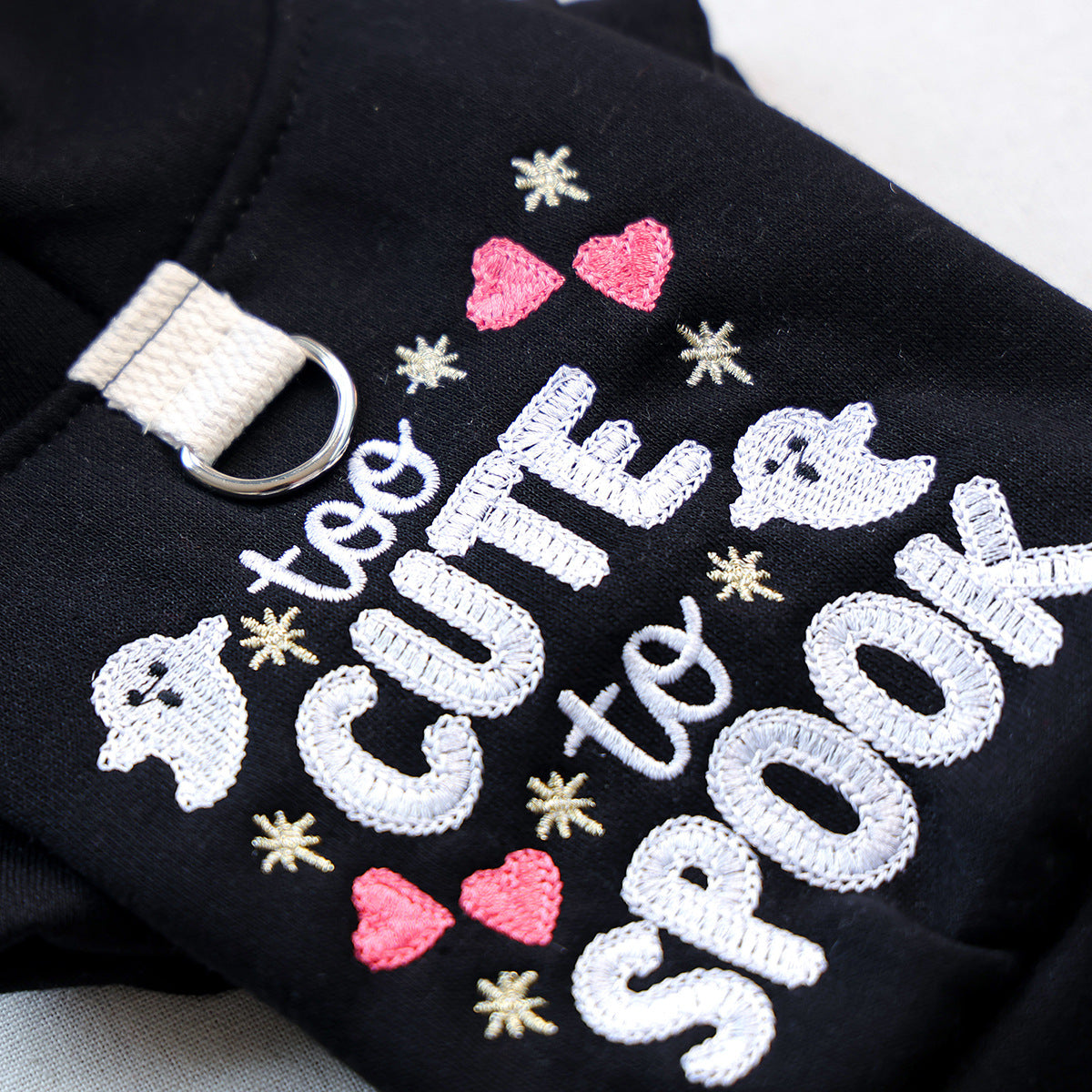Close-up of black Halloween pet hoodie with white ghost and pink heart embroidery