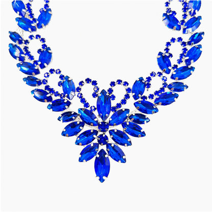 Blue pet necklace close-up with flower center, leaf-shaped jewel-style accents, and silver-tone setting