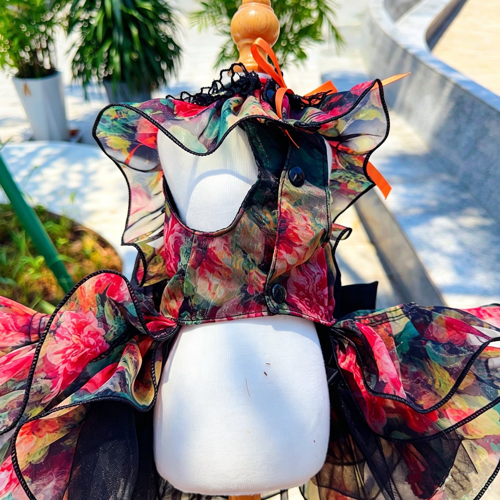 Close back view of multicolor floral tulle pet dress with buttons and orange ribbon