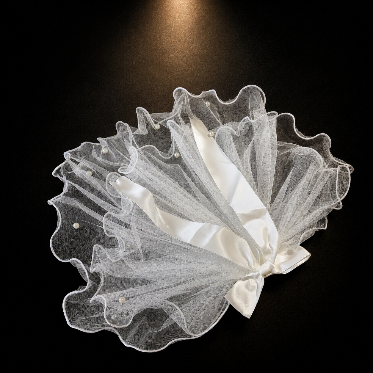 White tulle pet veil hair clip with sheer ruffles, white ribbon detail, and pearl accents on black background