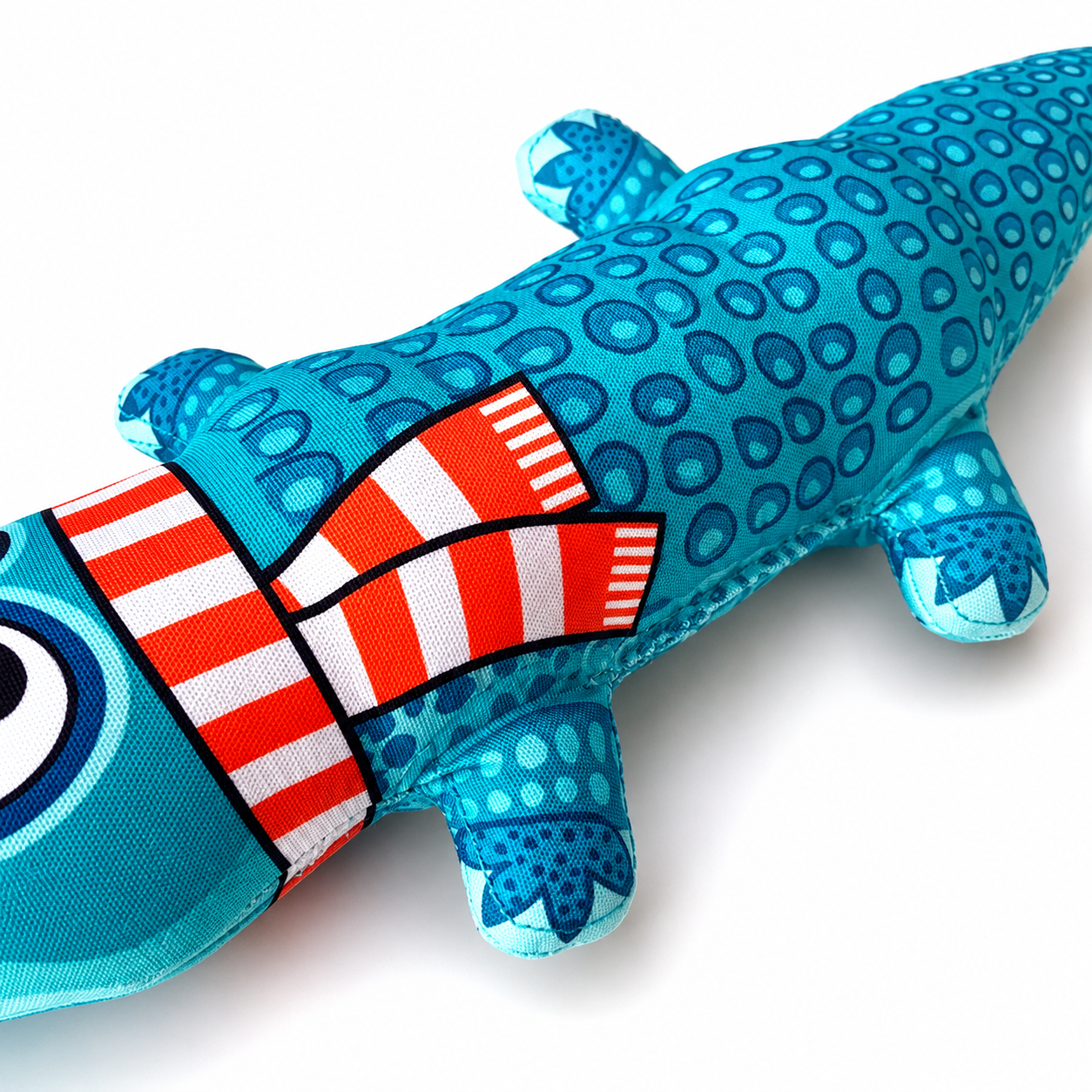 Close up of blue alligator plush dog toy body with red striped detail and printed scales