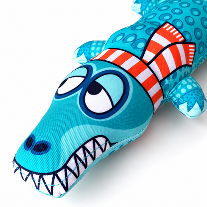 Close up of blue alligator plush dog toy face with cartoon eyes and teeth