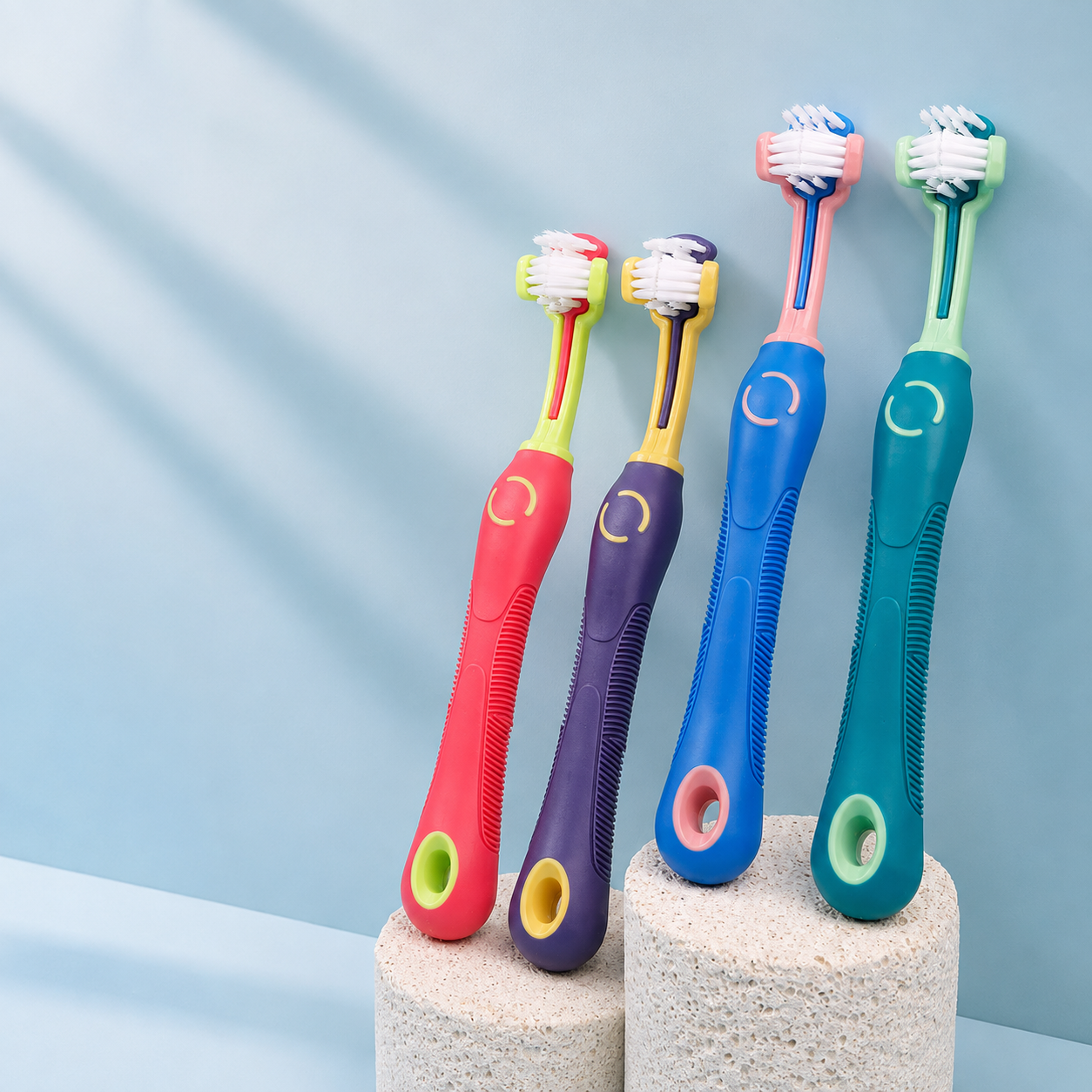 Four color three-sided pet toothbrushes for dogs and cats on blue display